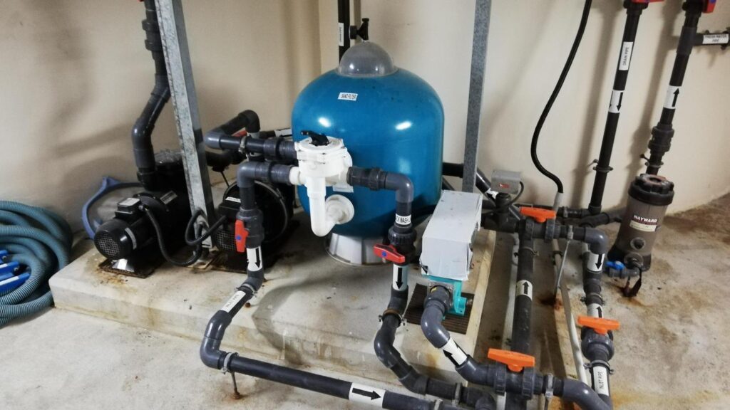 Water treatment equipment with a blue filter tank, pumps and valve manifolds