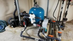 Water treatment equipment with a blue filter tank, pumps and valve manifolds