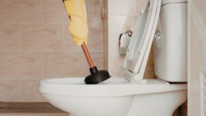 Plunger being used to clear a blocked toilet